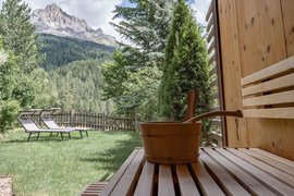 Saunaruimte met houten emmer, ligstoelen en bergzicht in de tuin