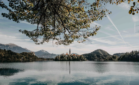 Uitzicht op een kerk op een eiland in een meer omringd door bergen en bomen