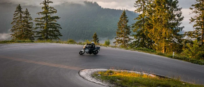 Motorradfahrer auf kurviger Bergstraße bei Sonnenaufgang