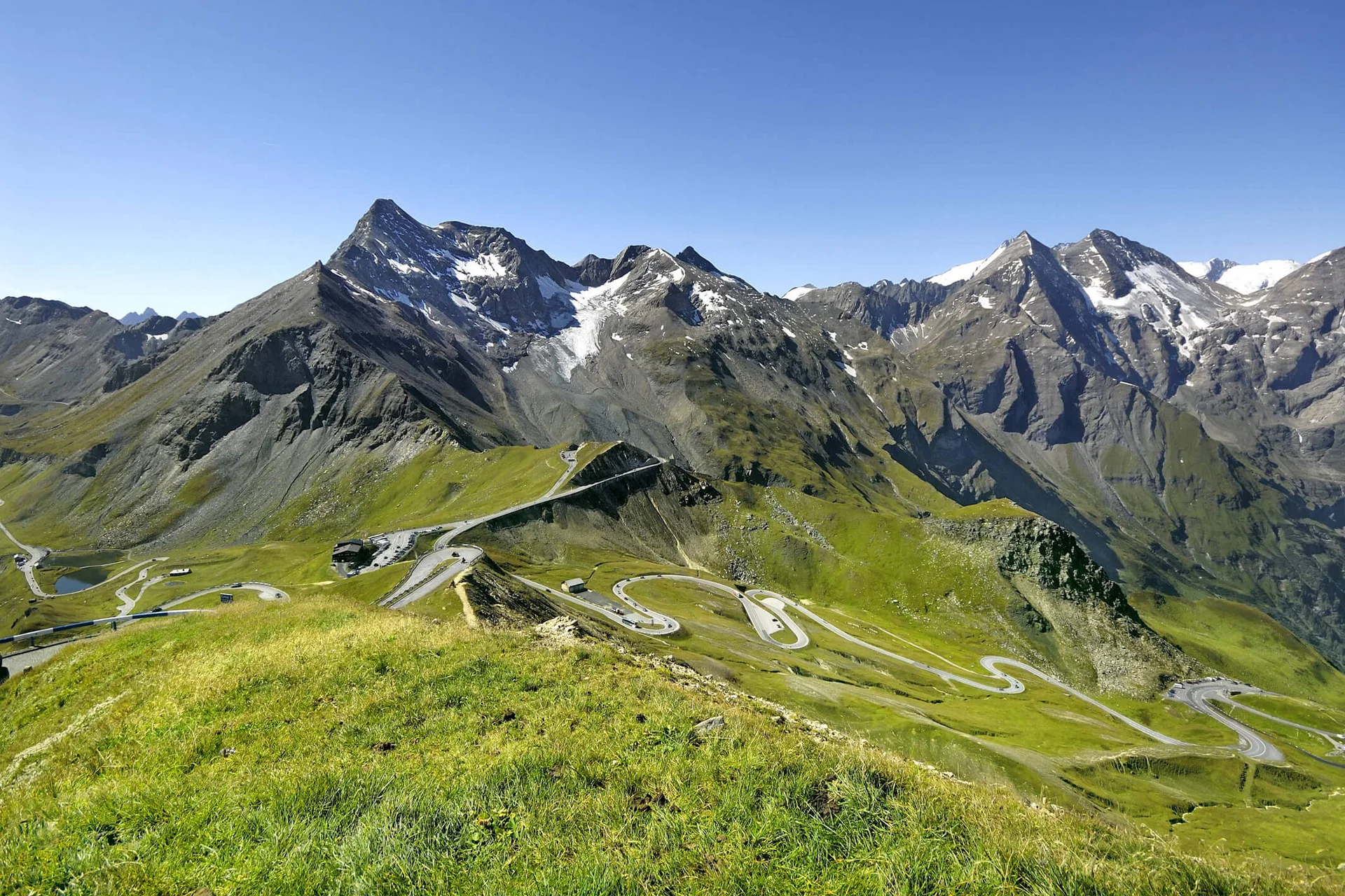 Motorbike holiday © Großglockner Hochalpenstraße Winding mountain road in green Alps with snow-capped peaks under clear blue sky