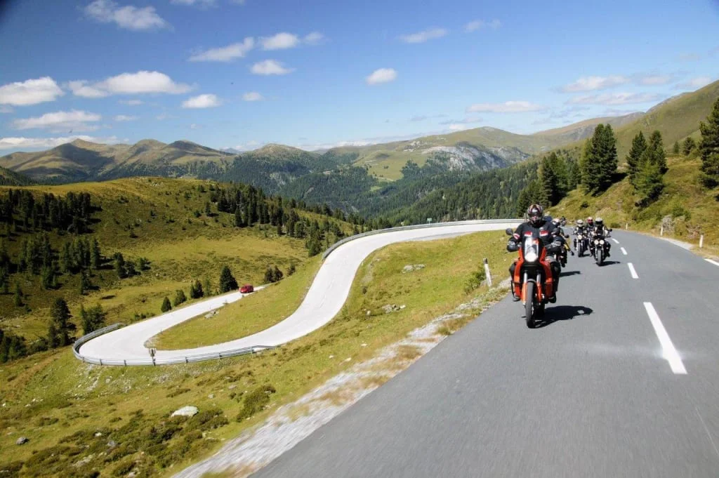 Motorcyclists riding on a winding mountain road on a sunny day