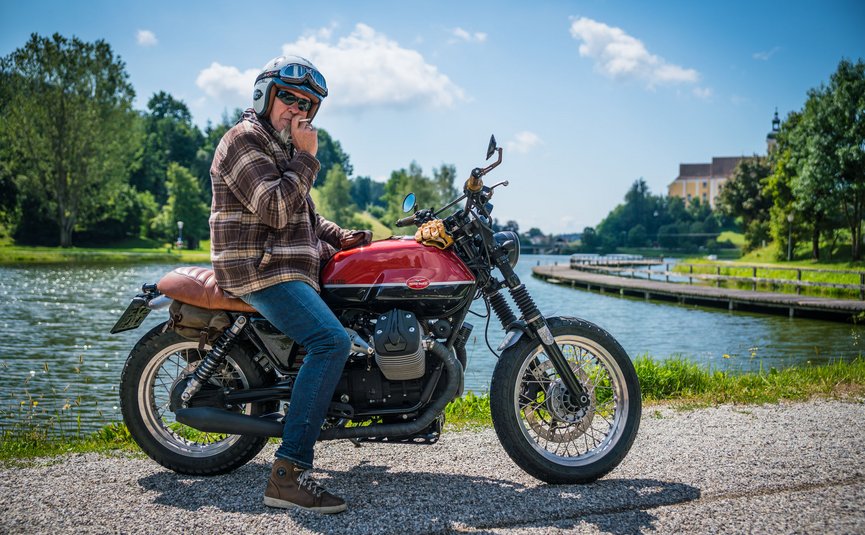 Gasthof Pension Drei Hacken *** © Moppetfoto.de Mann mit Helm auf Motorrad an Flussufer bei sonnigem Wetter
