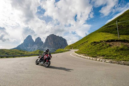 Motorradfahrer auf Bergstraße mit Felsen und bewölktem Himmel