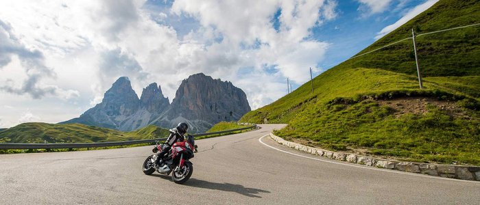 Hotel Florian ***S © Arik Oberrauch Motorradfahrer auf Bergstraße mit Felsen und bewölktem Himmel