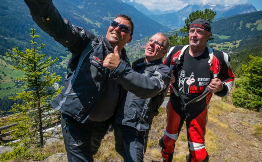 Drei Motorradfahrer machen Selfie mit Berglandschaft im Hintergrund