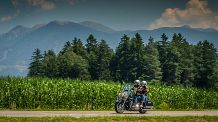 3 Zinnen – Kronplatz – Eisacktal © Moppetfoto.de Zwei Motorradfahrer fahren auf Landstraße vor Wald und Bergen