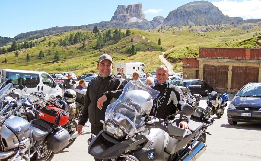 King of the curves offer - as of € 218,- per person Two men with motorcycles in mountainous area on a sunny day