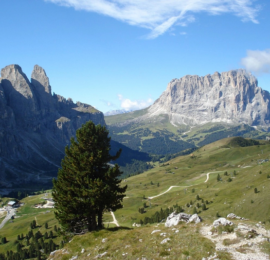 Blick auf grüne Hügel und steile Felsen unter blauem Himmel