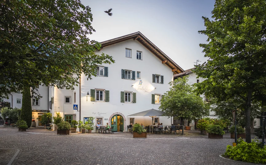 Cafe with outdoor seating in a cobblestone square surrounded by trees