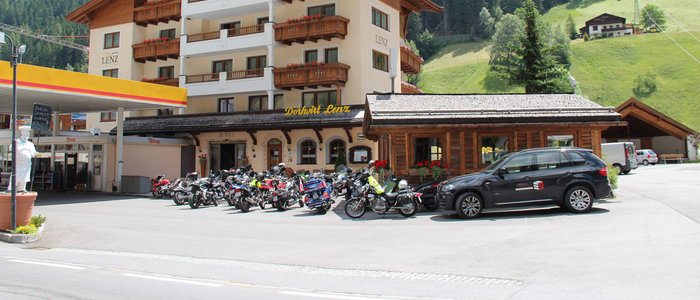 Hotel mit Motorrädern und Auto an einer Tankstelle im Bergdorf
