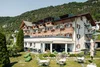Sammelanfragen © Ivan Bortondello Hotelgebäude mit Terrasse, Gartenmöbeln und Bergen im Hintergrund