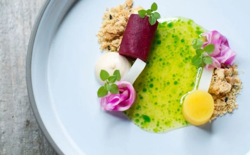 Mooi opgemaakt gerecht met groenten en groene saus op wit bord