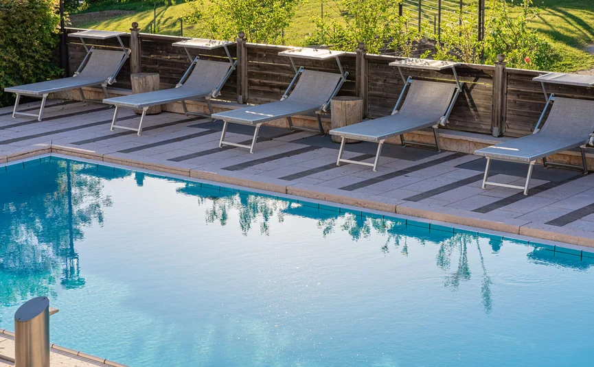 Cristallo Sport & Wellness Hotel **** © Andrea Acler Leere Poolliegen neben einem Schwimmbecken an einem sonnigen Tag