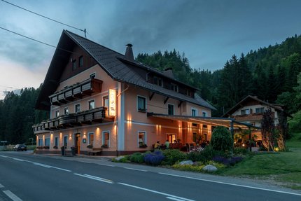 Hotel-Gasthof Strasswirt © Hotel Gasthof Strasswirt Beleuchtetes Gasthaus am Straßenrand in bewaldeter Gebirgslandschaft bei Abenddämmerung