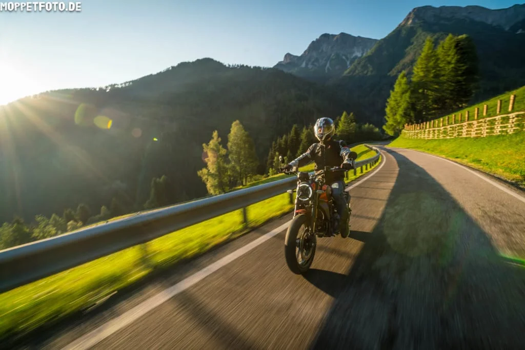 Dolomiti Motorbike Days Motorrijder op een bochtige bergweg met Alpenpieken op de achtergrond