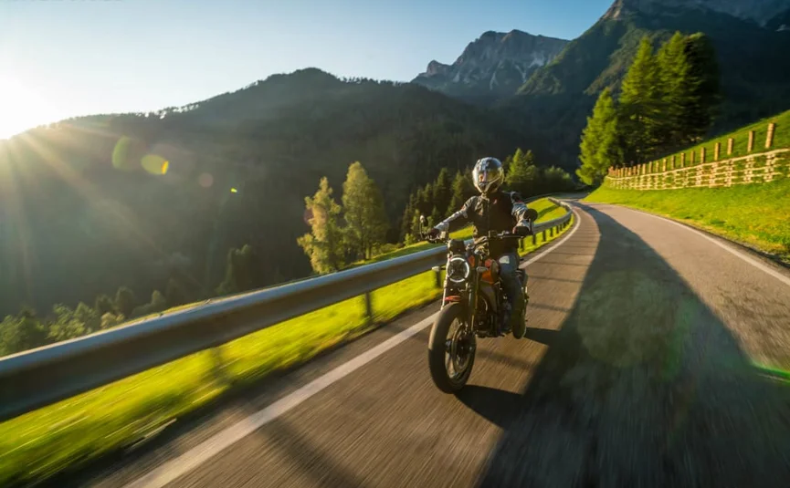 Dolomiti Motorbike Days Motorrijder op een bochtige bergweg met Alpenpieken op de achtergrond