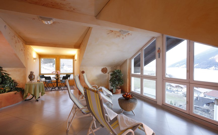 Hotel am Reschensee *** © The Dilitz Company GmbH Heller Raum mit Liegestühlen und Panoramafenster mit Bergblick