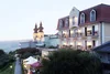 Sammelanfragen © Hotel Rose Hotelgebäude mit beleuchteten Balkonen und Kirche mit doppelten Türmen im Hintergrund