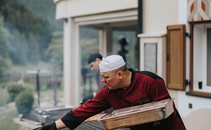 Koch bereitet Fleisch auf großem Grill im Freien vor