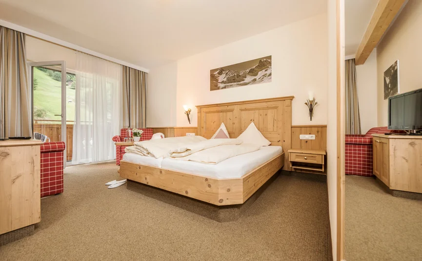 Cozy hotel room with wooden furniture and balcony overlooking green meadow