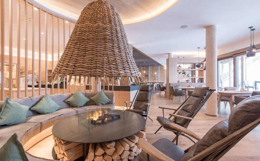 Modern waiting area with fireplace, sofas, and chairs in light wood design