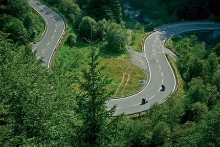 Winding mountain road with two motorcycles surrounded by green trees