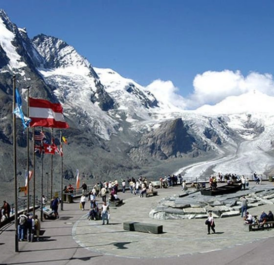 Touristen am Großglockner mit Nationalflaggen und schneebedeckten Alpen