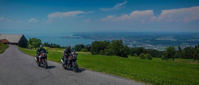 Zwei Motorradfahrer auf Landstraße mit Blick auf See und Landschaft