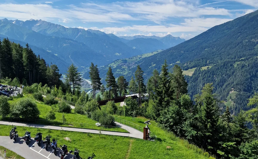 Motorcycles parked by road with mountain landscape under blue sky