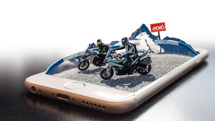 Motorradfahrer auf Bergstraße erscheinen aus Smartphone-Display