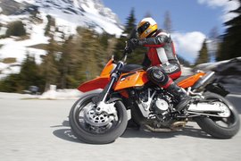 Motorradfahrer in Berglandschaft mit Schnee auf orangefarbenem Motorrad