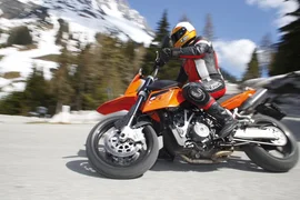 4 Touren Bike Woche Motorrijder op oranje motorfiets op bergweg met besneeuwde bomen