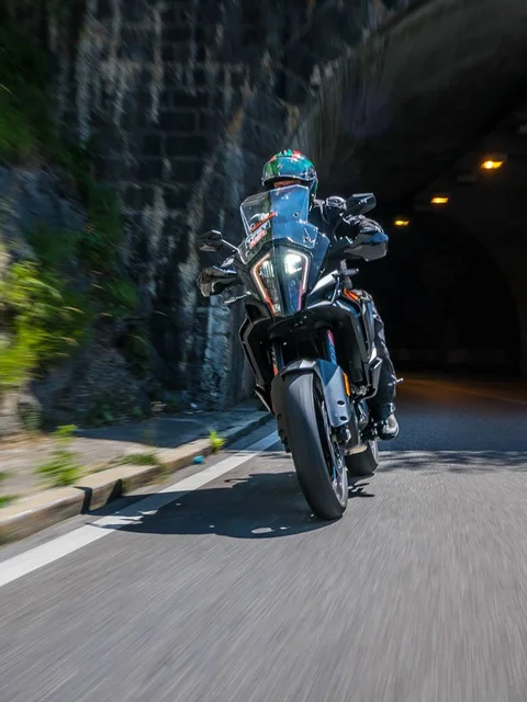 Motorcyclist riding through a tunnel beside a rocky wall
