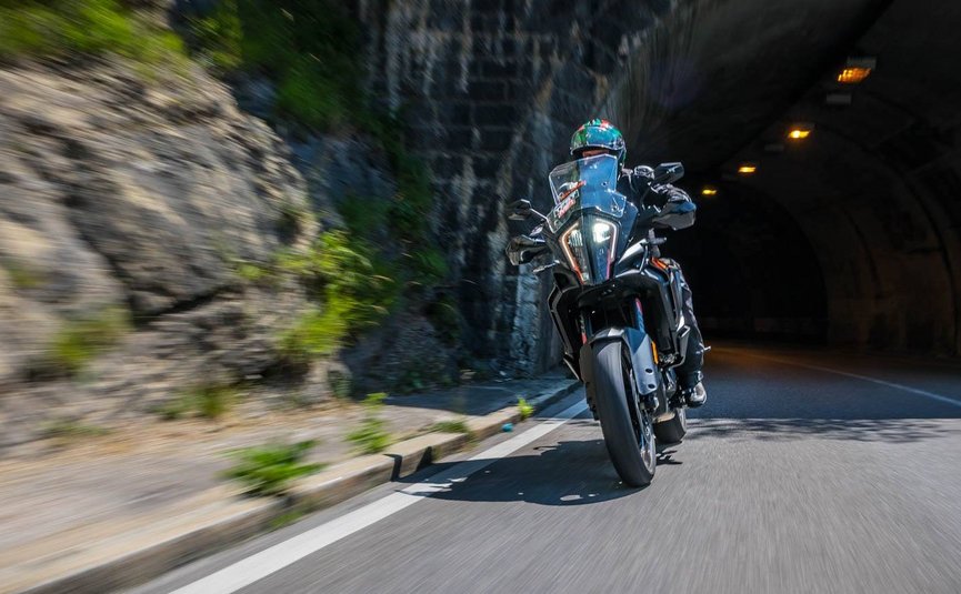 Motorradfahrer fährt in einem Tunnel an Felswand vorbei