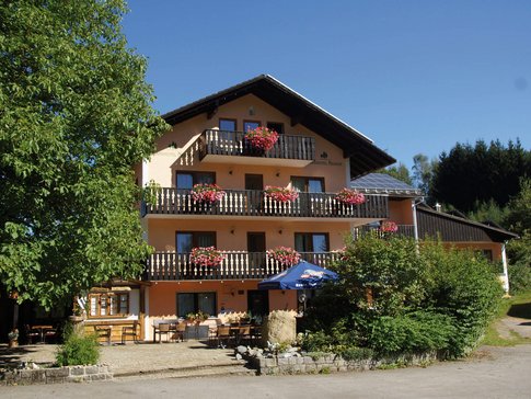 Landhotel Neuhof © Landhotel Neuhof Zenting Drei stöckiges Hotel mit Balkonen und Blumen unter blauem Himmel