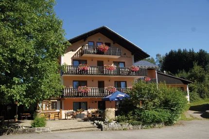 Three-story hotel with balconies and flowers under clear blue sky