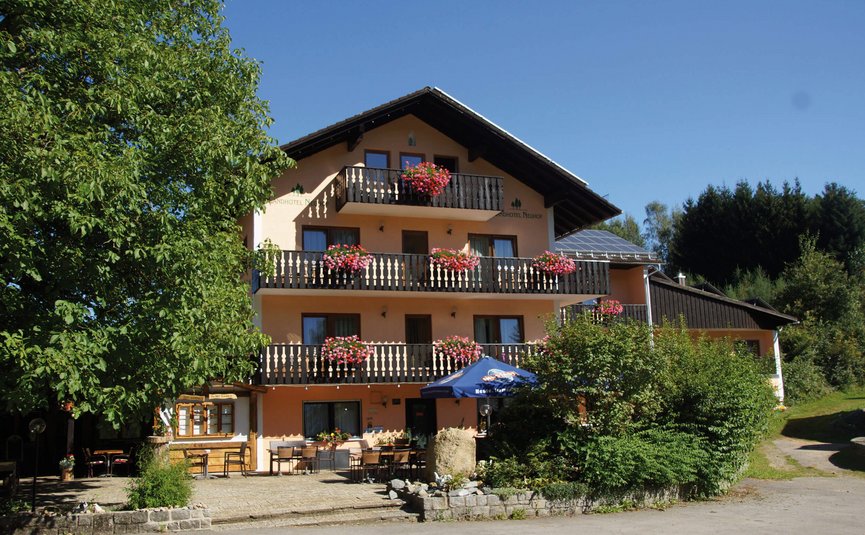 Drei stöckiges Hotel mit Balkonen und Blumen unter blauem Himmel