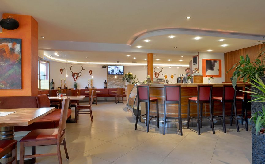 Moderner Restaurantinnenraum mit Bar, Holzmöbeln und dekorativen Pflanzen