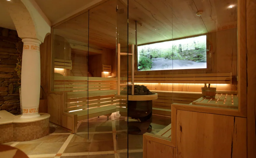 Modern sauna with wooden benches, glass door and digital nature image on the wall