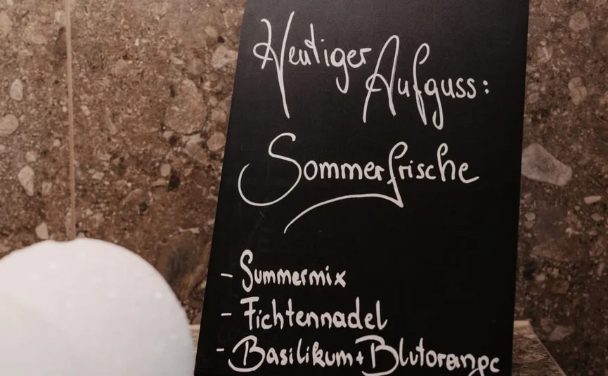 Sweaty Weekends Zwart bord met zomerinfusie en ingrediëntenlijst op muur van marmer