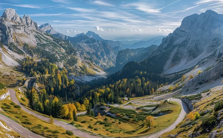 Winding mountain road in the Alps with autumn trees and rocky peaks