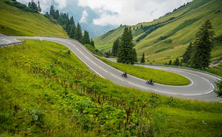 Motorfietsen op kronkelende bergweg omgeven door groene heuvels