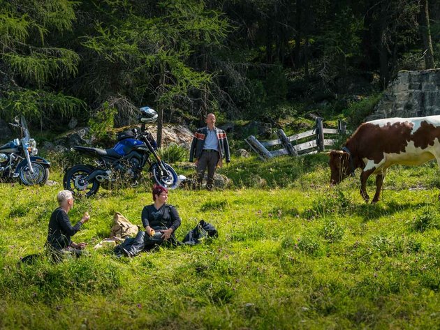 Qualitätsversprechen © Moppetfoto.de Menschen pausieren auf einer Wiese neben Motorrädern und Kühen im Wald