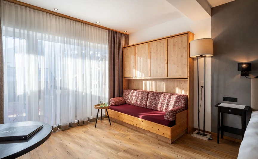 Living room with sofa, lamp, table and large windows with curtains