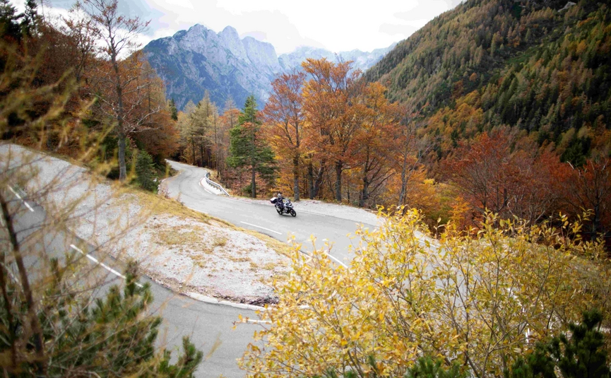 Motorfietser op kronkelende bergweg door herfstbos