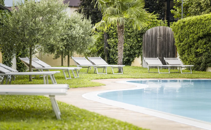 Swimming pool with lounge chairs surrounded by green trees and bushes