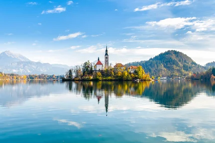 Church island on calm lake with mountains and blue sky in background