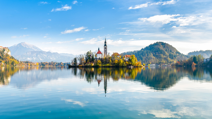 Bleeder See Kircheninsel auf einem ruhigen See mit Bergen und blauem Himmel im Hintergrund