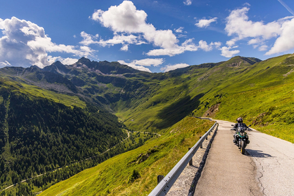Motorradfahrer auf Bergstraße mit Blick auf grüne Täler und Berge