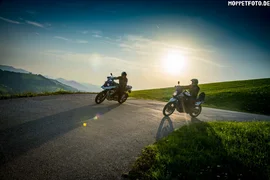 Two motorcyclists on a mountain road at sunset